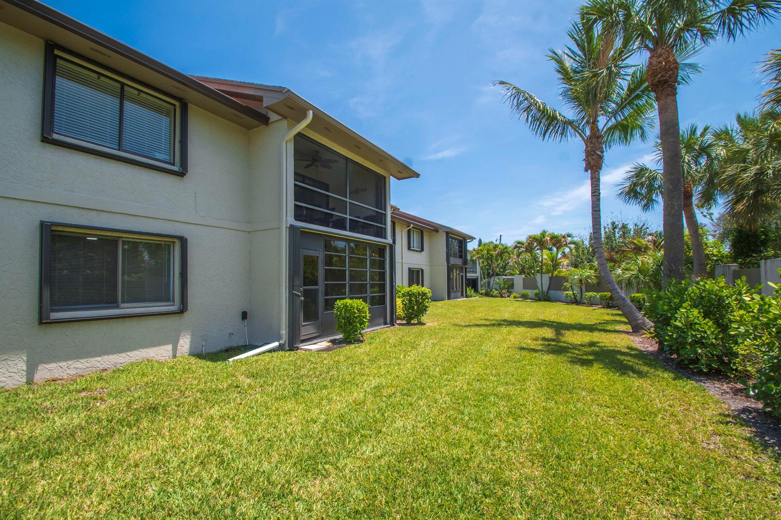 The exterior of a two-story apartment building with a screened-in patio and grassy lawn — 1600 NE Dixie Highway # 103, Jensen Beach FL 34957, JENSEN BEACH, FL