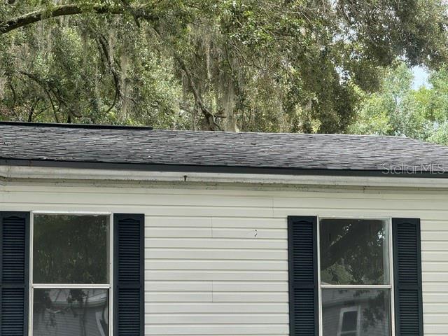 The exterior of a house features white horizontal siding, two windows with shutters, and shingles — 6633 GLEN MEADOW LOOP, LAKELAND, FL