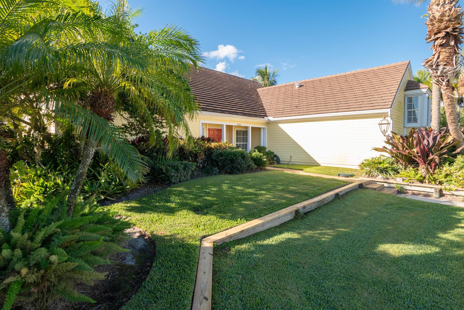 A yellow two-story house with a screened porch and a white fence in the yard — 3360 SE Golf Trail, Stuart FL 34997, STUART, FL