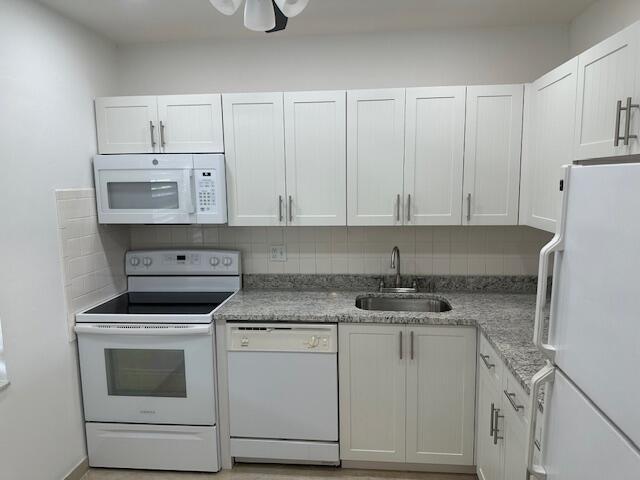 A kitchen features white cabinets, granite countertops, and white appliances — 7805 W Atlantic Boulevard # 202, Margate FL 33063, MARGATE, FL