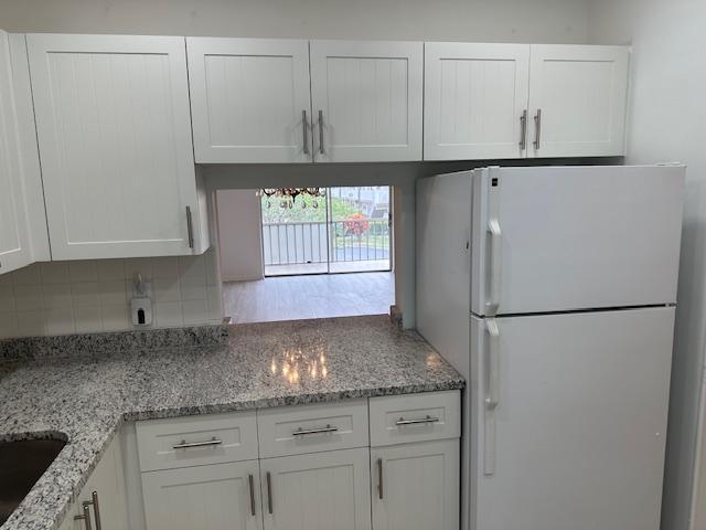 A kitchen features white cabinets, granite countertops, and a pass-through window overlooking a balcony — 7805 W Atlantic Boulevard # 202, Margate FL 33063, MARGATE, FL