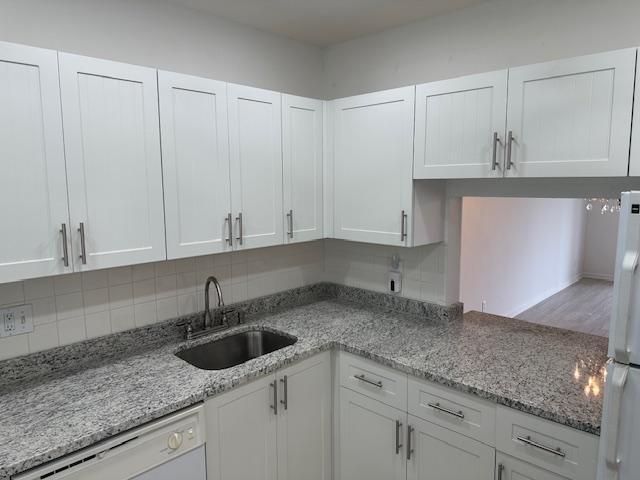 A kitchen features white shaker-style cabinets, granite countertops, and a stainless steel sink — 7805 W Atlantic Boulevard # 202, Margate FL 33063, MARGATE, FL