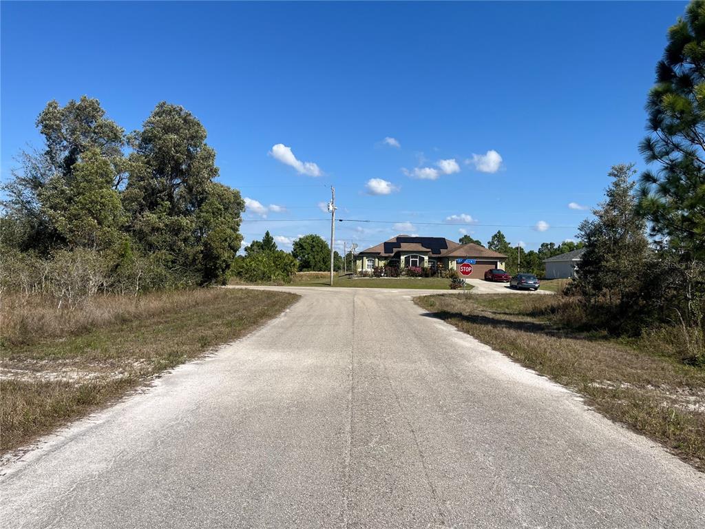 A paved road leads toward a house with solar panels and a stop sign — 1247 BRUNELL AVENUE, FORT MYERS, FL