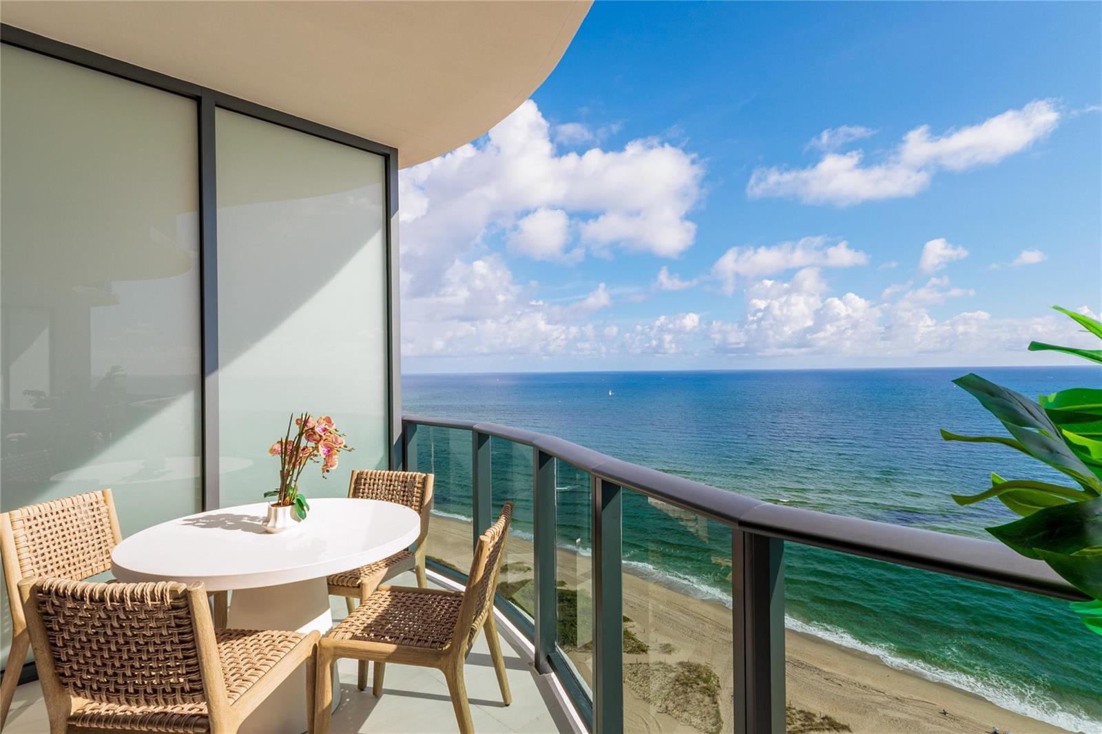A balcony with a round table and chairs overlooks the ocean and sandy beach — 900 N Ocean Boulevard, Pompano Beach FL 33062, POMPANO BEACH, FL