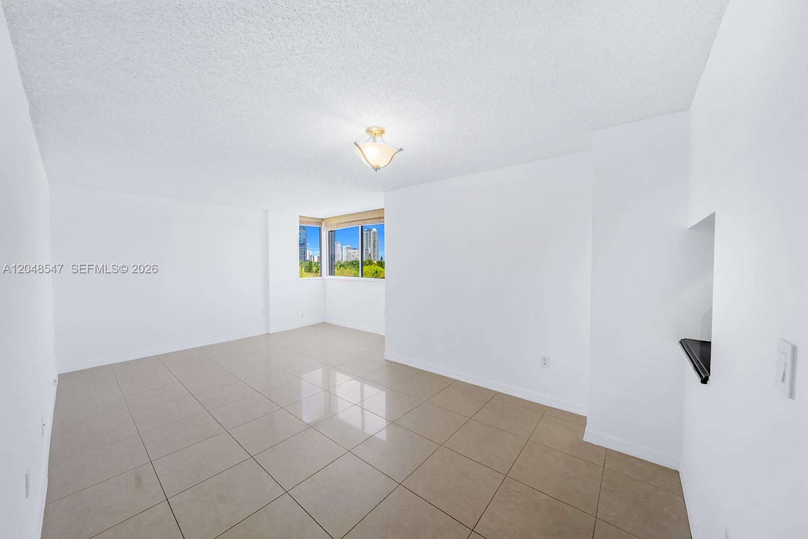 An empty room with white walls, beige tile flooring, and a corner window view — 2400 SW 3rd Ave # 706, Miami FL 33129, MIAMI, FL