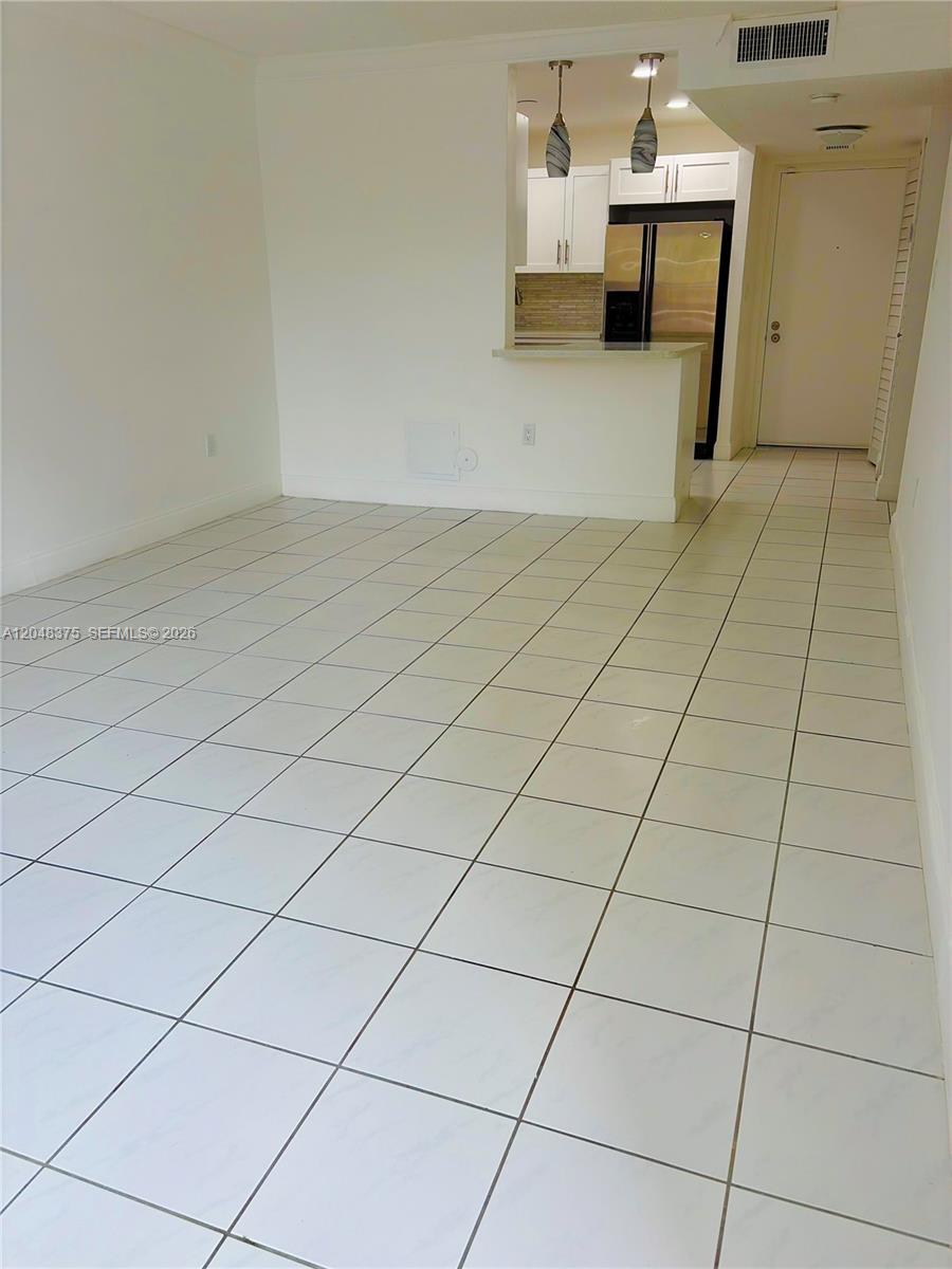 An open-concept living area features white tile flooring and a pass-through kitchen with pendant lighting — 5705 W 20th Ave # 101, Hialeah FL 33012, HIALEAH, FL