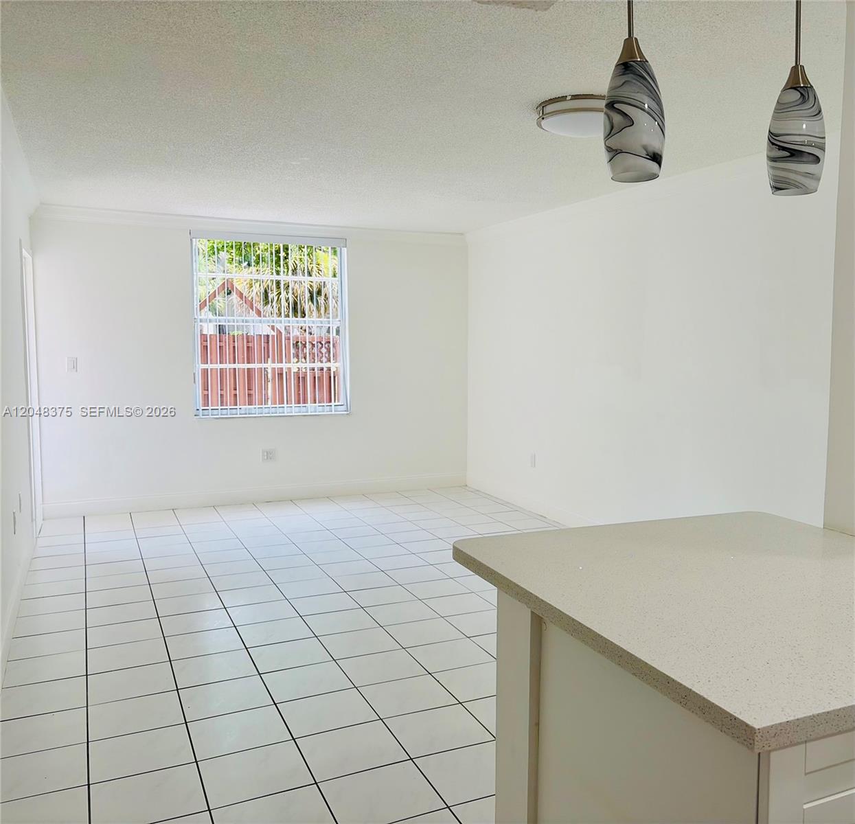 An empty room with white tile floors, white walls, and two pendant lights — 5705 W 20th Ave # 101, Hialeah FL 33012, HIALEAH, FL