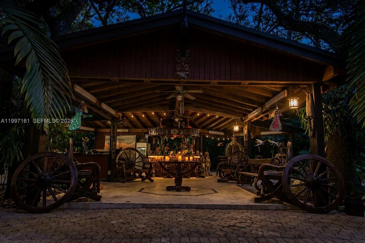 A wooden house with a stone chimney and a thatched-roof gazebo under a full moon — 15425 SW 268th St, Homestead FL 33032, HOMESTEAD, FL