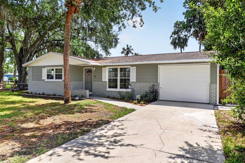 A single-story house with gray siding, brick accents, a white garage door, and a driveway — 7212 WEDGEWOOD DRIVE, NEW PORT RICHEY, FL
