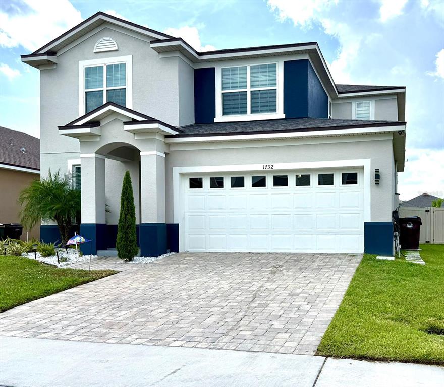 A two-story house with a gray and blue exterior, a paved driveway, and a garage — 1732 FLOURISH AVENUE, KISSIMMEE, FL