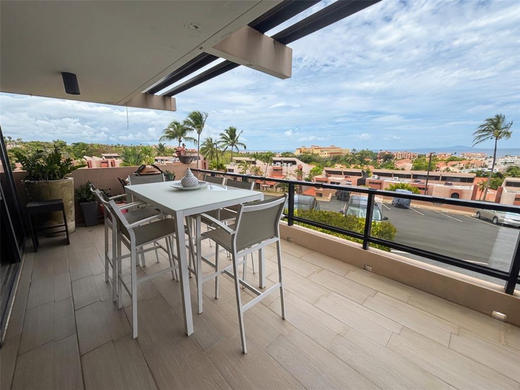 A balcony features a dining set, tile flooring, and a glass railing overlooking a resort — 170 PALMAS  DRIVE DRIVE UNIT B14, HUMACAO, PR