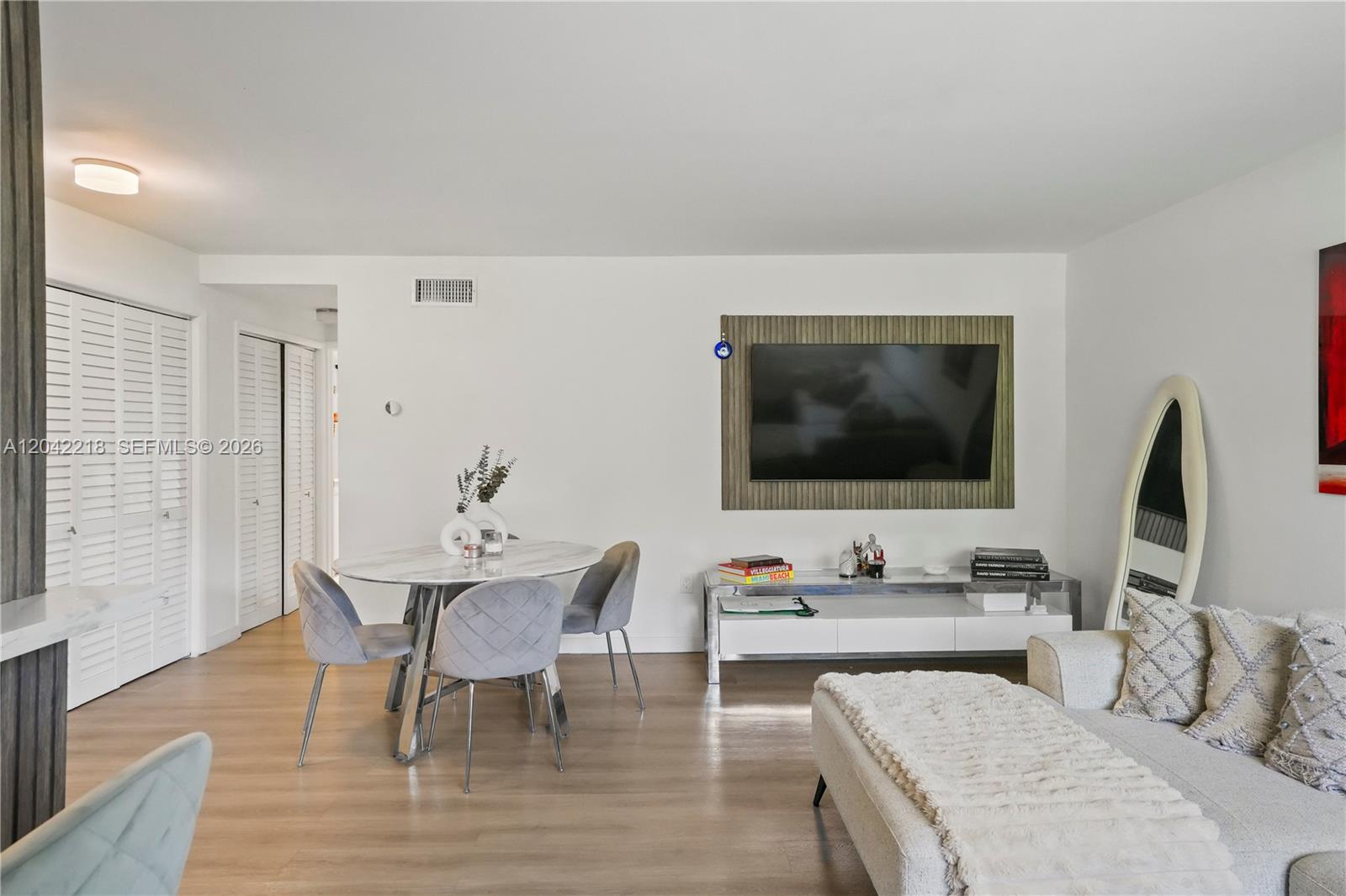 A living and dining area features a wall-mounted television, a round table, and light flooring — 1614 West Ave # 203, Miami Beach FL 33139, MIAMI BEACH, FL