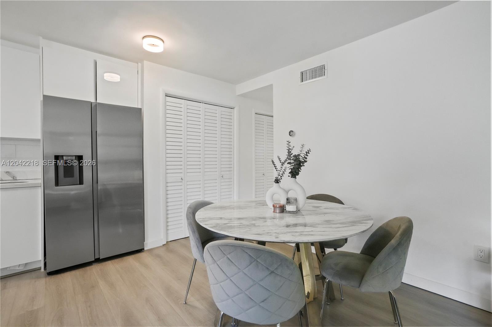 A dining area features a round marble table, four grey chairs, and a stainless refrigerator — 1614 West Ave # 203, Miami Beach FL 33139, MIAMI BEACH, FL