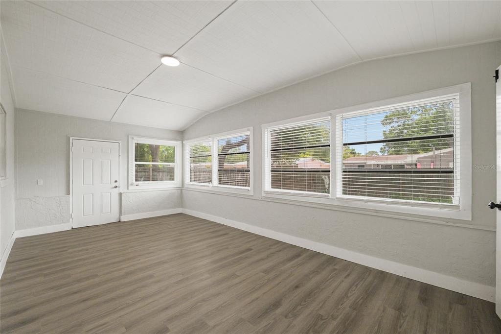 A sunroom with light gray walls, wood-look flooring, and multiple windows with blinds — 2952 WEBLEY DRIVE, LARGO, FL