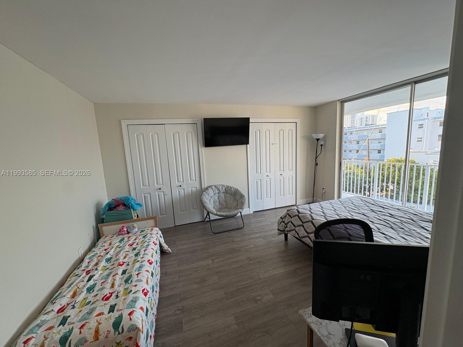 A bedroom features a bed, a twin bed, two closets, and a balcony with city views — 910 Michigan Ave # 505, Miami Beach FL 33139, MIAMI BEACH, FL