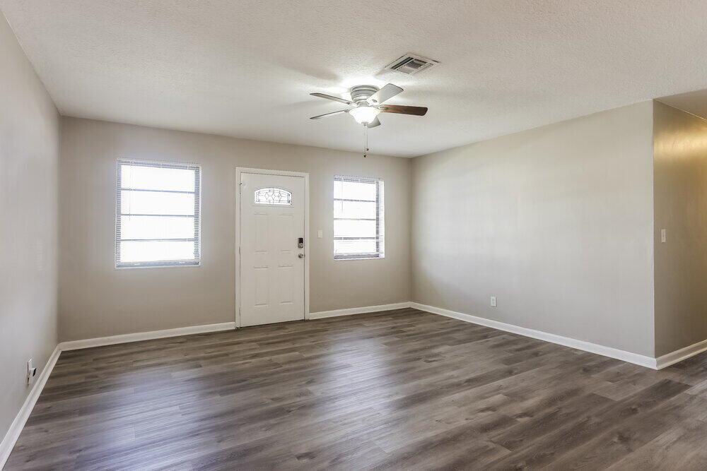An empty room with light gray walls, wood-look flooring, a ceiling fan, and two windows — MIAMI GARDENS, FL