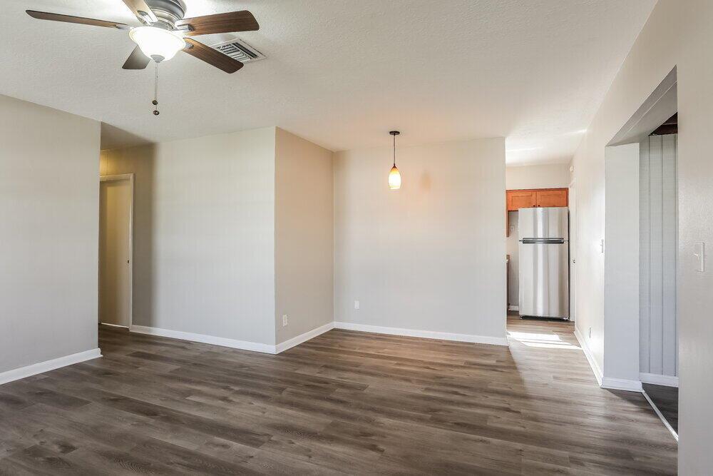 An open-concept living and dining area features light gray walls and wood-look laminate flooring — MIAMI GARDENS, FL