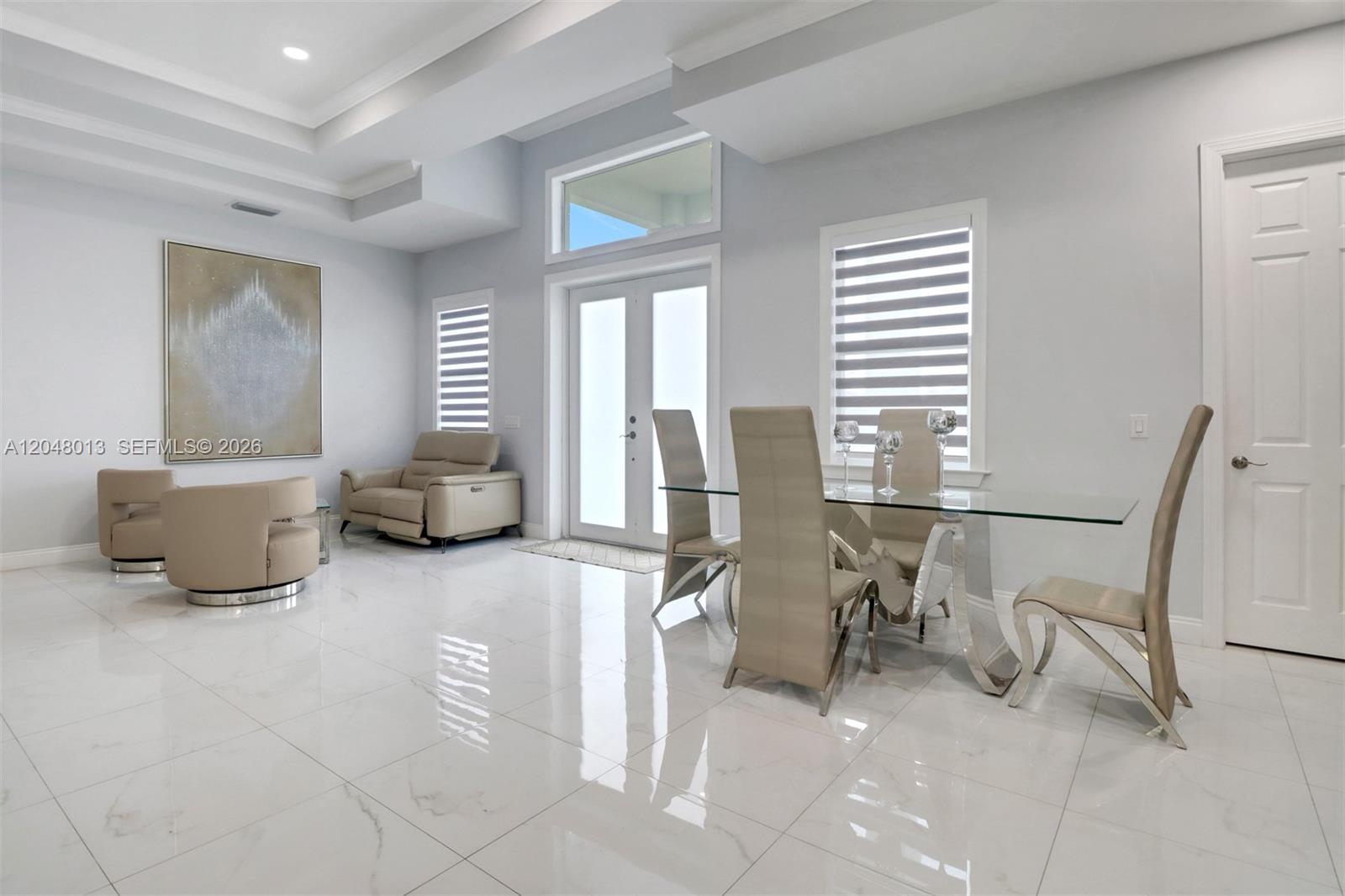 A bright dining and living area features white tile floors, high ceilings, and modern furniture — 2394 45th Avenue NE, Naples FL 34120, NAPLES, FL