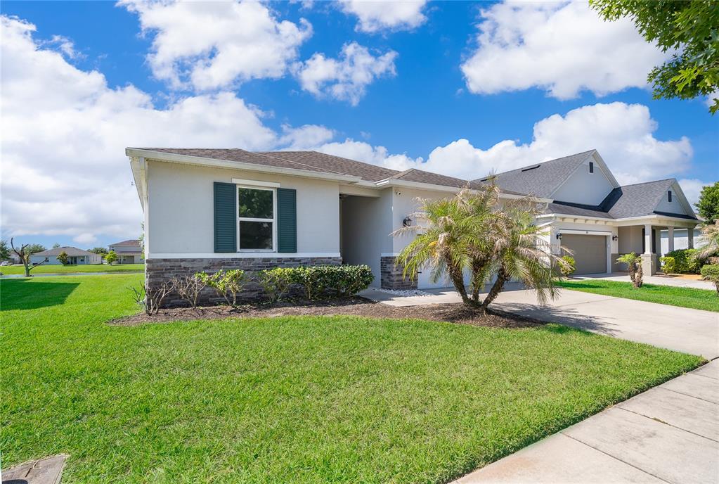 A single-story house with a stone-accented facade, green shutters, and a palm tree in front — 1815 PLUMAS WAY, ORLANDO, FL