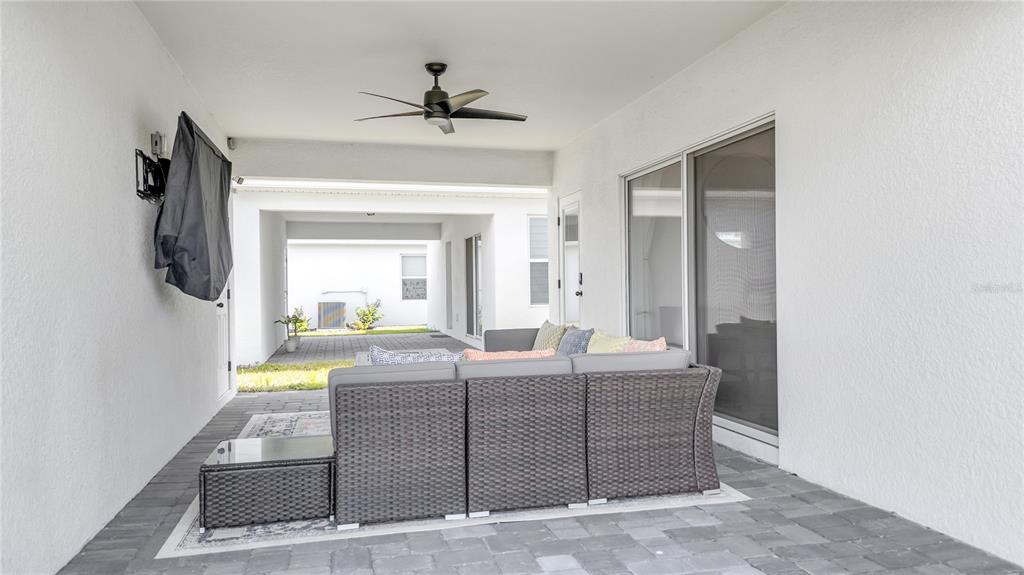 A covered patio features gray wicker furniture, a ceiling fan, and a paved floor — 10836 WATERWOOD ALLEY, ORLANDO, FL