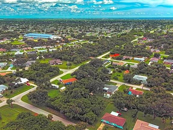 An aerial view shows a residential neighborhood with scattered houses, dense trees, and roads — 21511 CARLETON AVENUE, PORT CHARLOTTE, FL