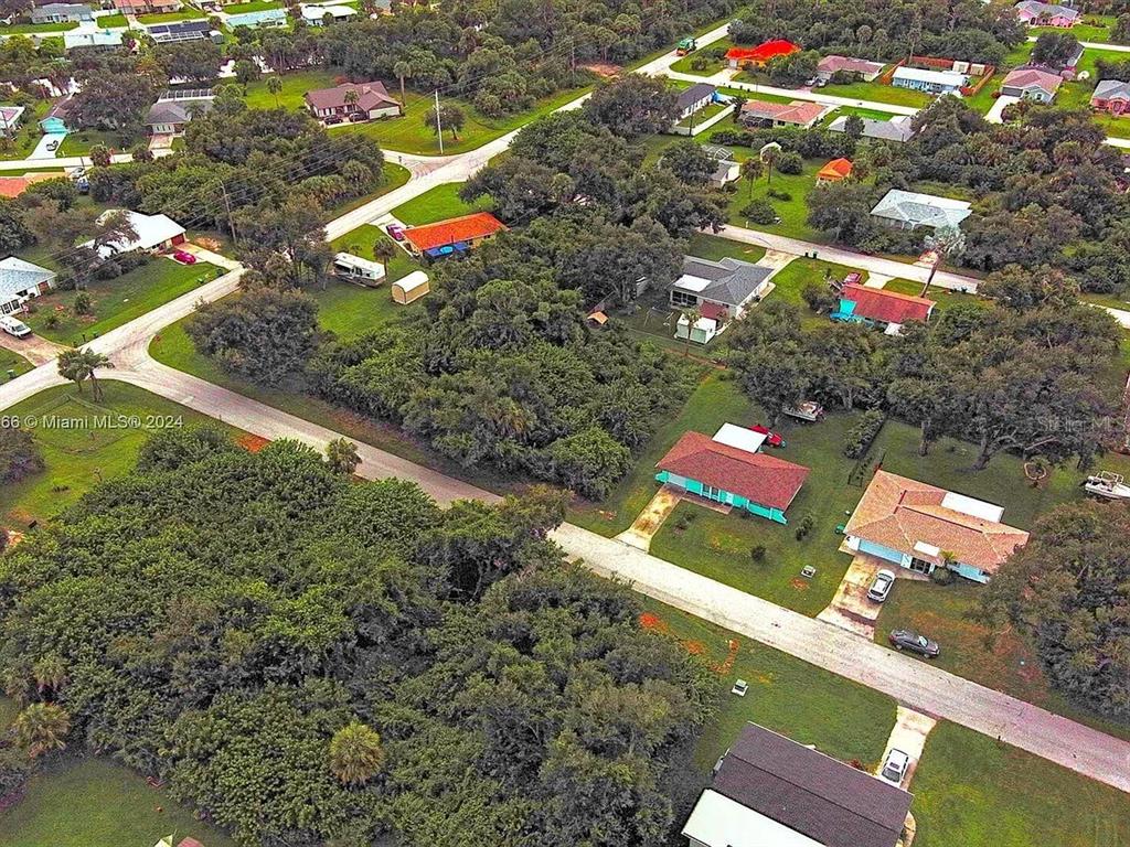 An aerial view shows several single-family homes surrounded by dense trees and paved roads — 21511 CARLETON AVENUE, PORT CHARLOTTE, FL