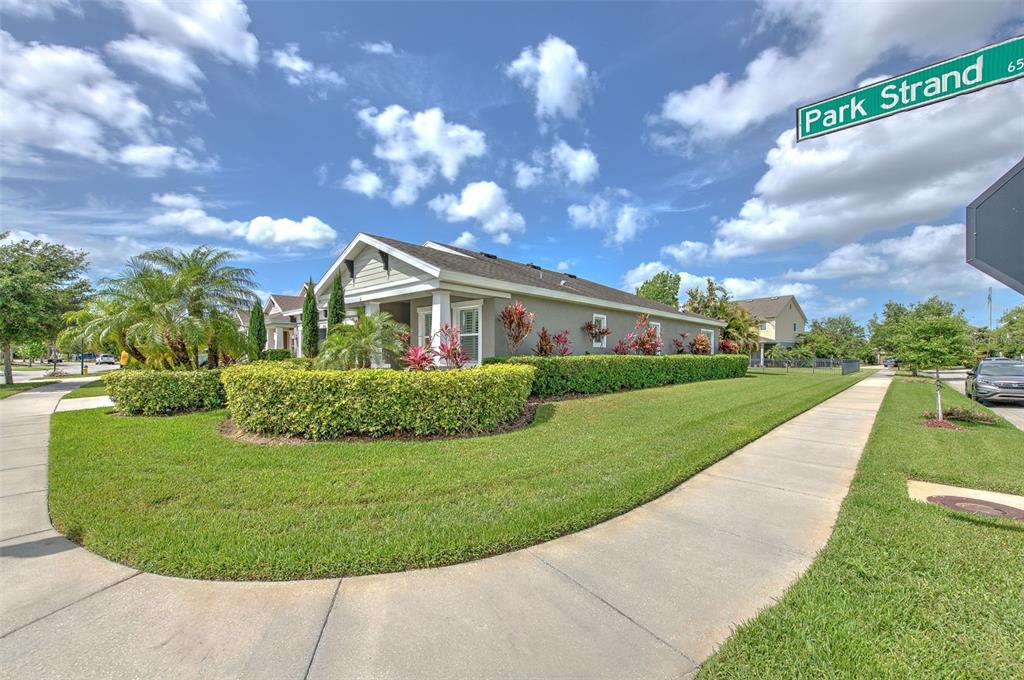 A single-story house with a manicured hedge and lawn sits on a corner lot — 6540 PARK STRAND DRIVE, APOLLO BEACH, FL