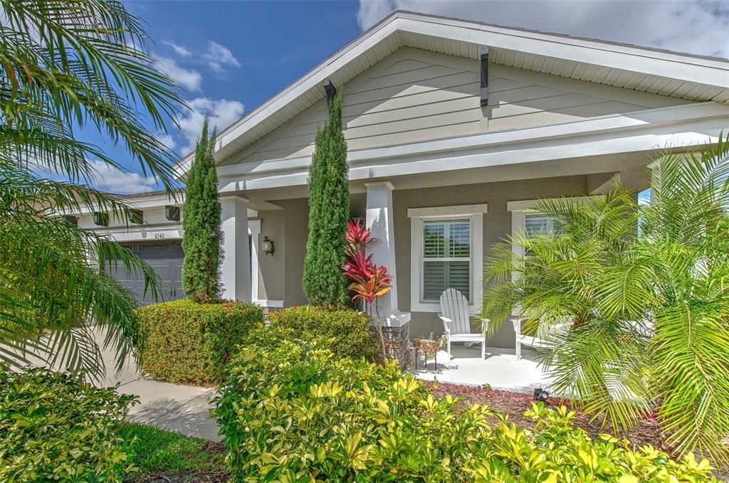 A single-story house exterior features a covered front porch, landscaping, and a two-car garage — 6540 PARK STRAND DRIVE, APOLLO BEACH, FL