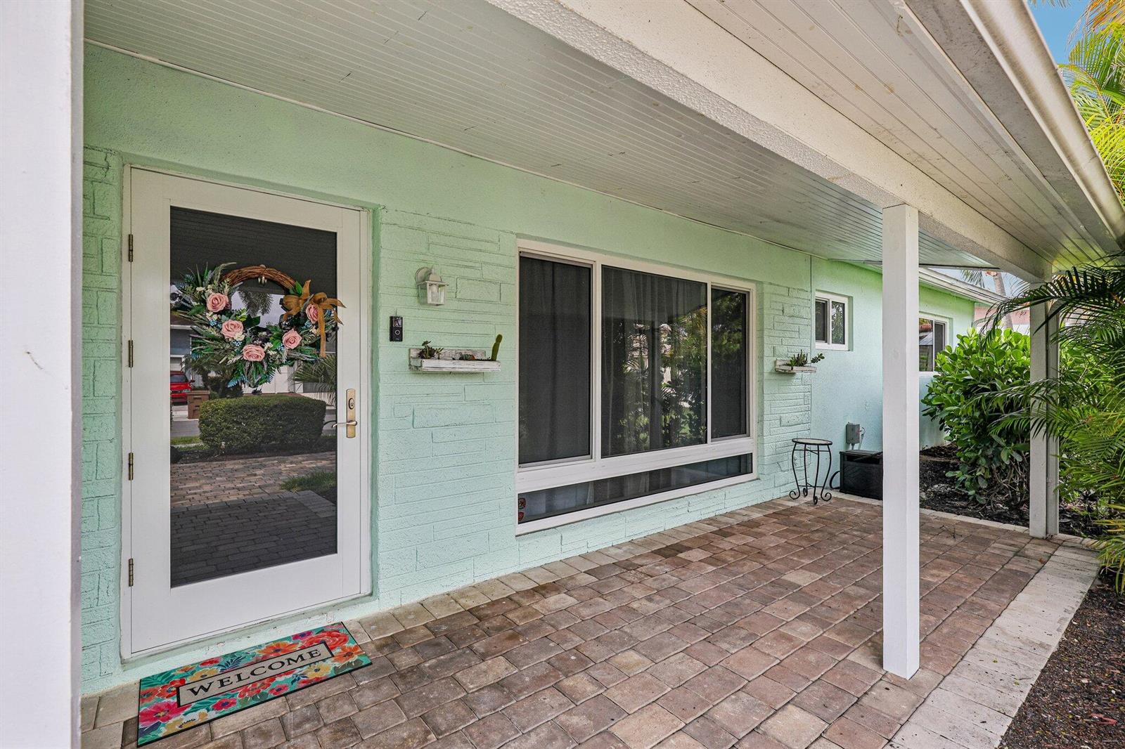 A light green brick house exterior features a covered patio with brick pavers — 500 SE 8th Avenue, Deerfield Beach FL 33441, DEERFIELD BEACH, FL