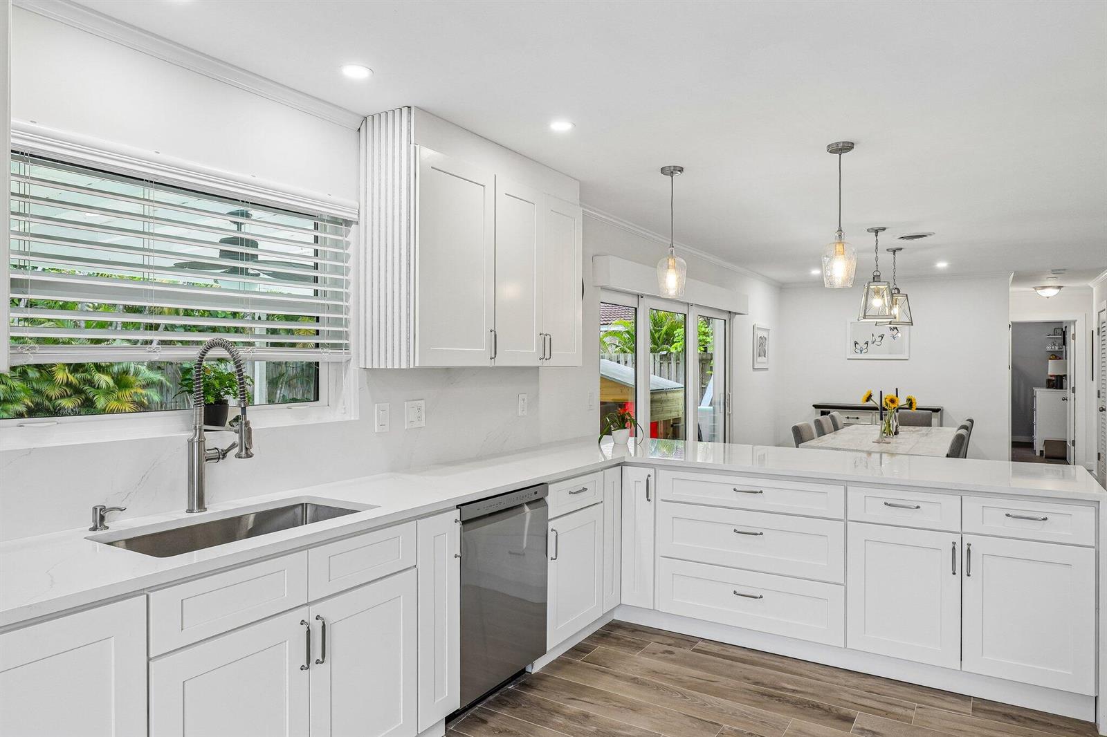 A modern white kitchen with quartz countertops, stainless steel appliances, and wood-look tile flooring — 500 SE 8th Avenue, Deerfield Beach FL 33441, DEERFIELD BEACH, FL