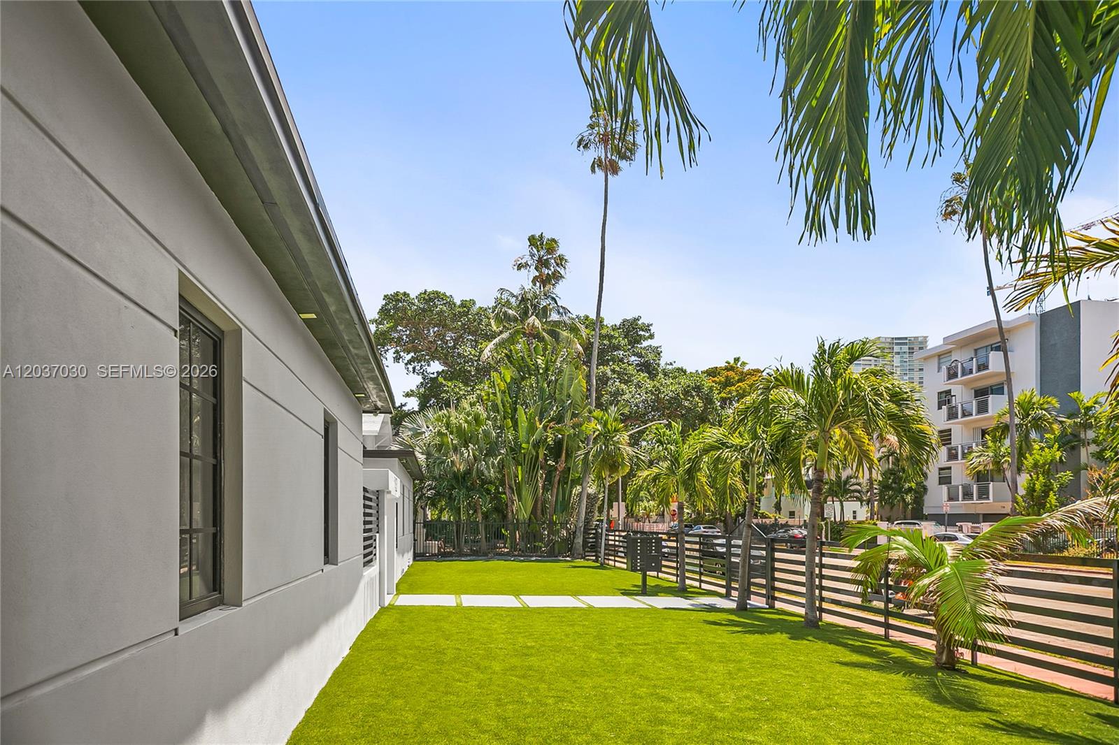 A side yard features artificial turf, a concrete walkway, and a black metal fence — MIAMI BEACH, FL
