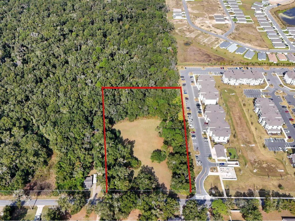An aerial view shows a rectangular plot of land outlined in red near a residential complex — 2495 NW NW 21ST STREET, OCALA, FL
