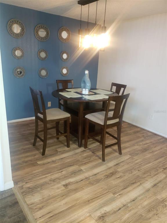 A dining area features a round wooden table, four chairs, and a blue accent wall — 2478 SWEETWATER CLUB CIRCLE UNIT 94, KISSIMMEE, FL
