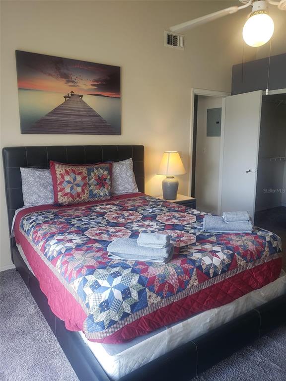 A bedroom features a bed with a patterned quilt, a lamp, and a wall-mounted picture — 2478 SWEETWATER CLUB CIRCLE UNIT 94, KISSIMMEE, FL