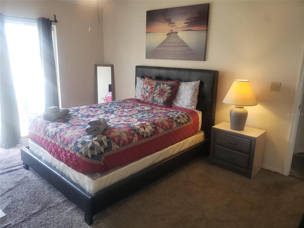 A bedroom features a bed with a patterned quilt, a dark headboard, and a nightstand — 2478 SWEETWATER CLUB CIRCLE UNIT 94, KISSIMMEE, FL
