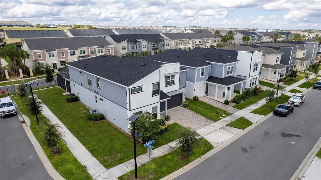 An aerial view shows modern two-story townhomes with gray siding and dark roofs in a neighborhood — 2312 SALTY WINDS WAY, KISSIMMEE, FL