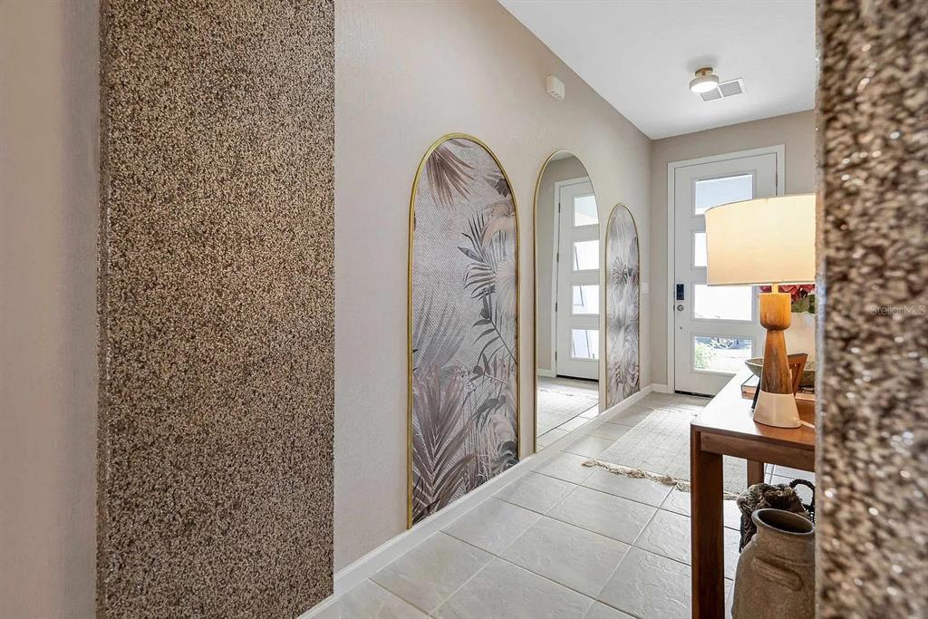 A hallway features arched wall panels with tropical wallpaper, textured accent walls, and tile flooring — 2312 SALTY WINDS WAY, KISSIMMEE, FL