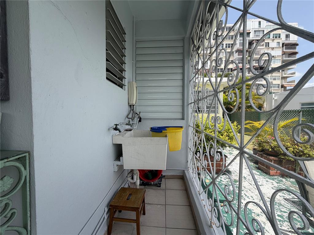A balcony features a utility sink, a small wooden stool, and decorative metal security bars — 559 CALLE AUSTRAL, SAN JUAN, PR