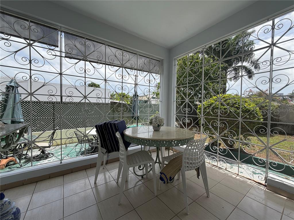 A tiled sunroom features a round table, white chairs, and decorative metal security grilles — 559 CALLE AUSTRAL, SAN JUAN, PR