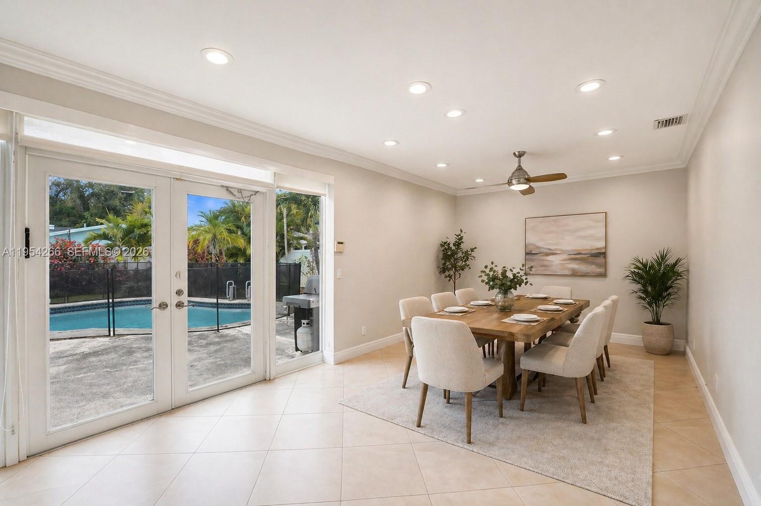 A dining room with a wooden table, light-colored chairs, and glass doors overlooking a pool — 3671 N 47th Ave, Hollywood FL 33021, HOLLYWOOD, FL