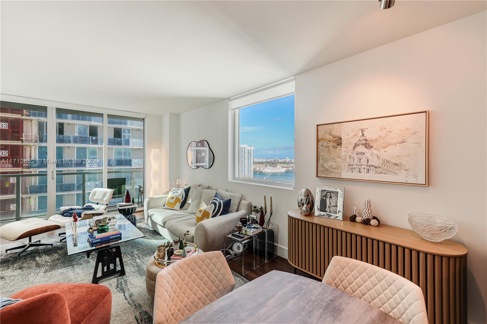 A modern living room features a glass coffee table, a sofa, and a city view — 55 SE 6th St # 3407, Miami FL 33131, MIAMI, FL
