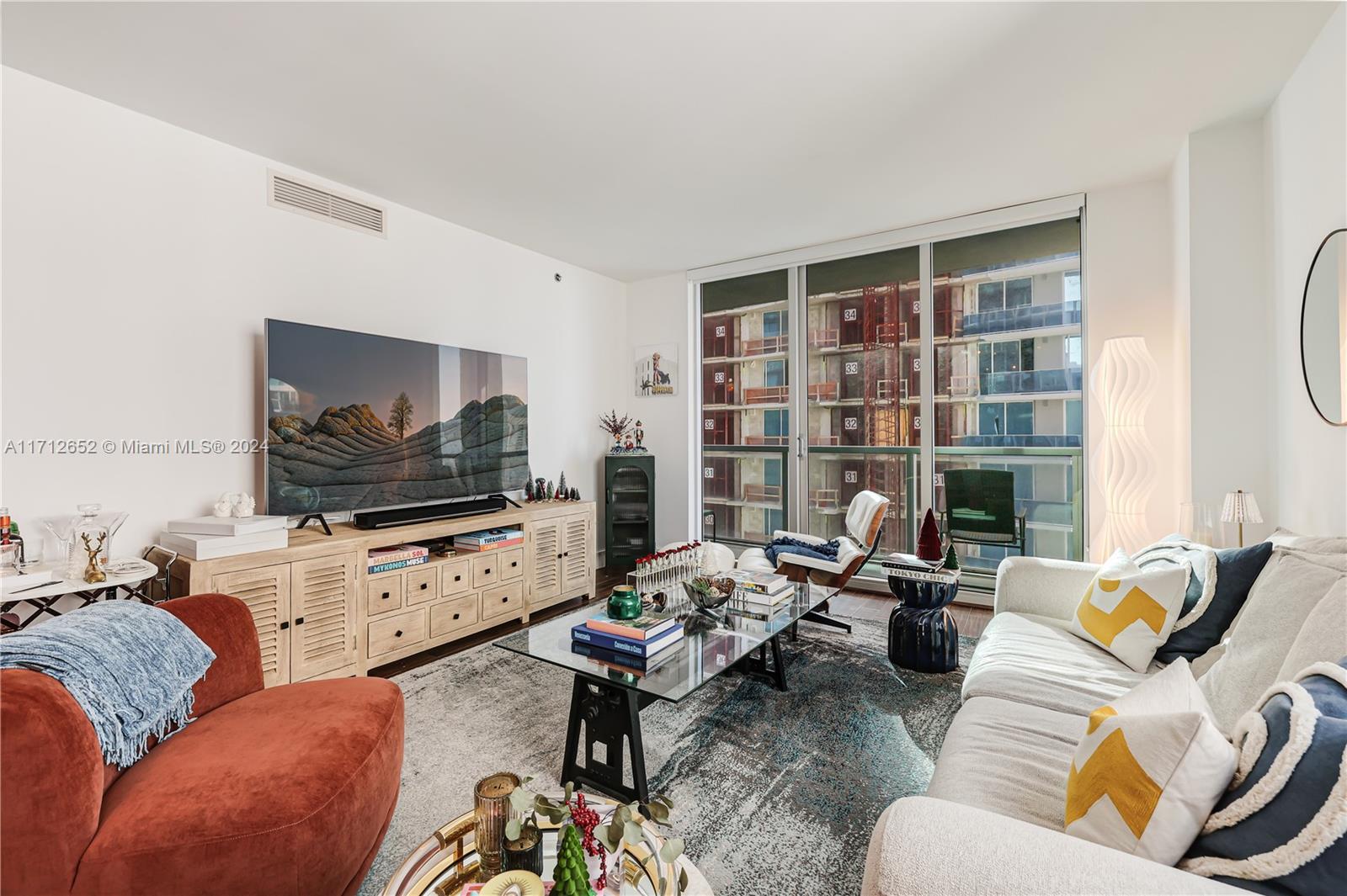 A living room features a large television, a glass coffee table, and a white sofa — 55 SE 6th St # 3407, Miami FL 33131, MIAMI, FL