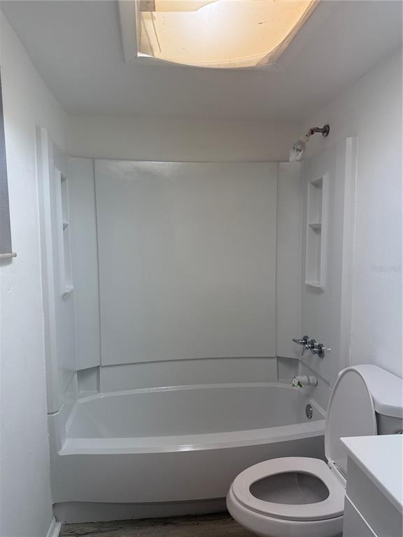 A bathroom featuring a white bathtub and shower surround, a toilet, and a skylight — 1264 113TH AVENUE UNIT J102, TAMPA, FL