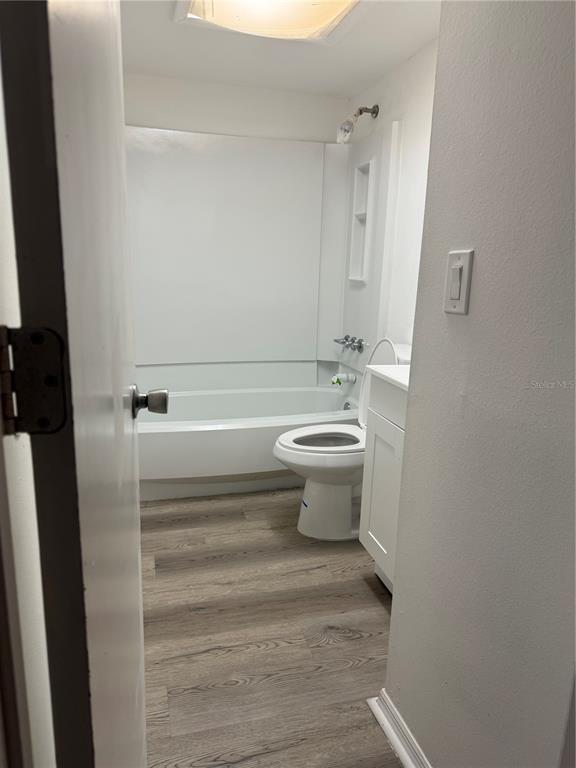 A bathroom features a white bathtub, a toilet, a vanity, and wood-look flooring — 1264 113TH AVENUE UNIT J102, TAMPA, FL
