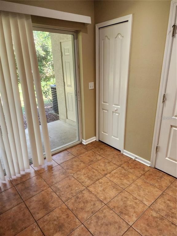A room with brown tile flooring, a sliding glass door, and two white interior doors — 15924 FISHHAWK CREEK LANE, LITHIA, FL