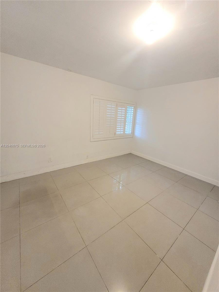An empty room features white walls, a single window with shutters, and light-colored tile flooring — 1132 Moffett St, Hallandale Beach FL 33009, HALLANDALE BEACH, FL
