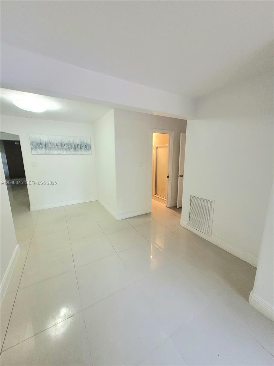 This interior space features white walls, light-colored tile flooring, and a doorway leading to a bathroom — 1132 Moffett St, Hallandale Beach FL 33009, HALLANDALE BEACH, FL