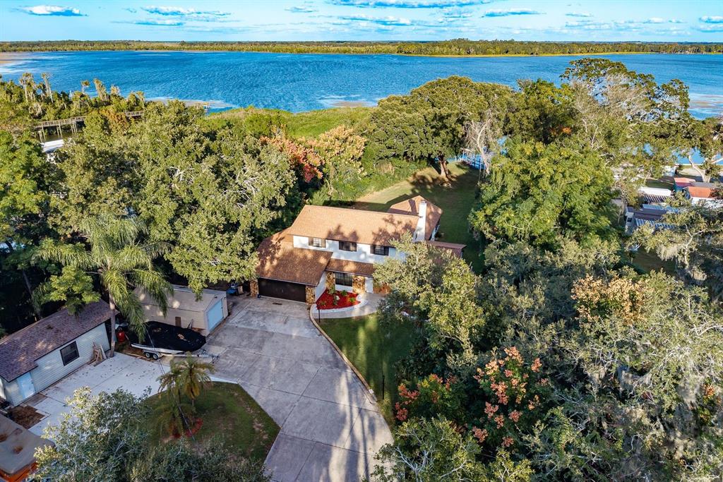 An aerial view shows a two-story house with a large driveway near a lake — 1416 GROVE AVENUE, LEESBURG, FL