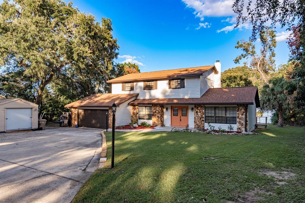 A two-story house with a stone facade, orange double doors, and an attached garage — 1416 GROVE AVENUE, LEESBURG, FL