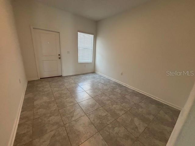 An empty room features light-colored walls, a white door, a window with blinds, and tiled floors — 2533 SKYLINE LOOP, KISSIMMEE, FL